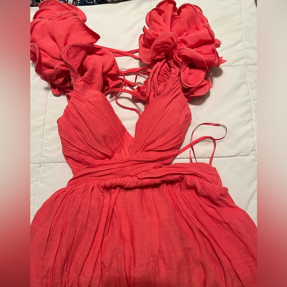 This is a pink/coral dress with ruffled sleeves, and a tie open back.